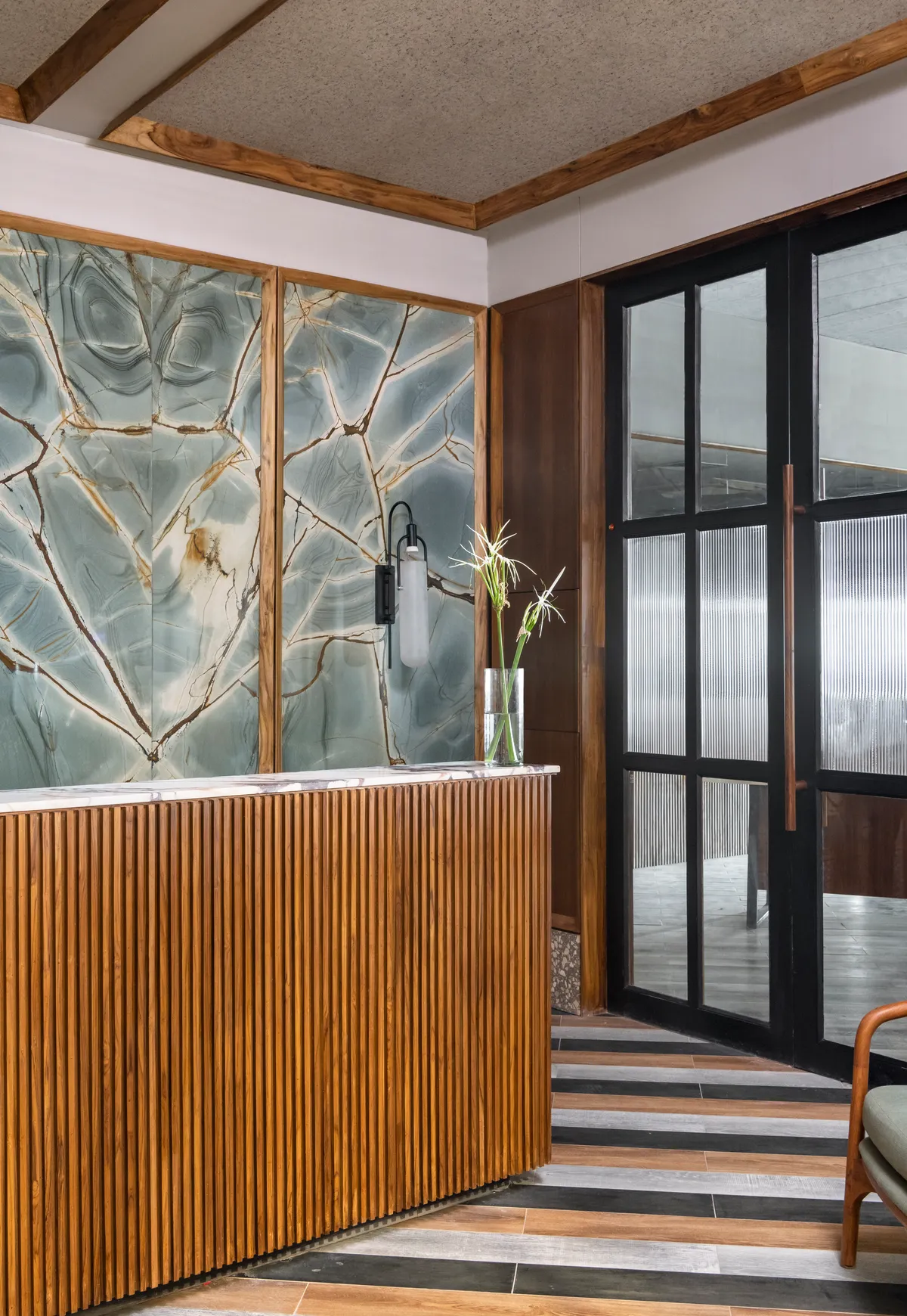 Reception at Unit 1009, Adventz Infinity @5 — slatted teak desk and stone wall